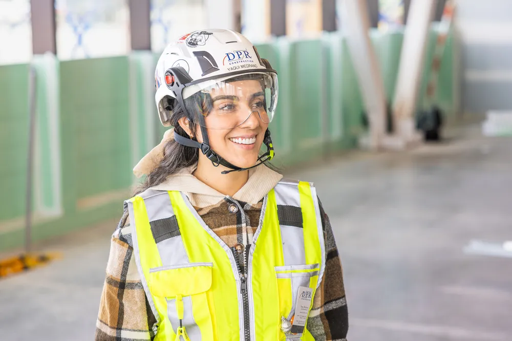 Trabajador sonriente empezando su carrera en una obra con un casco.
